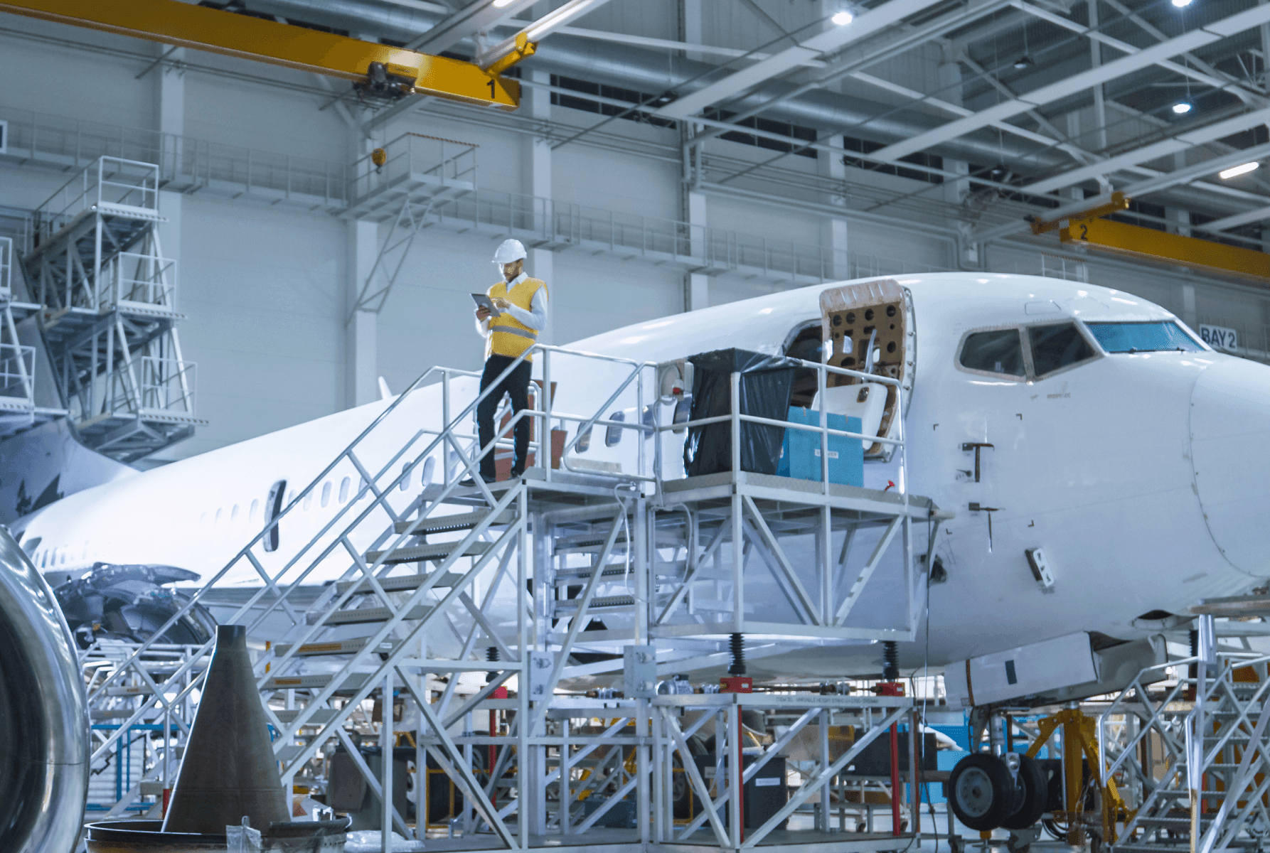 Man stood taking notes on ipad on top of platform next to an aeroplane