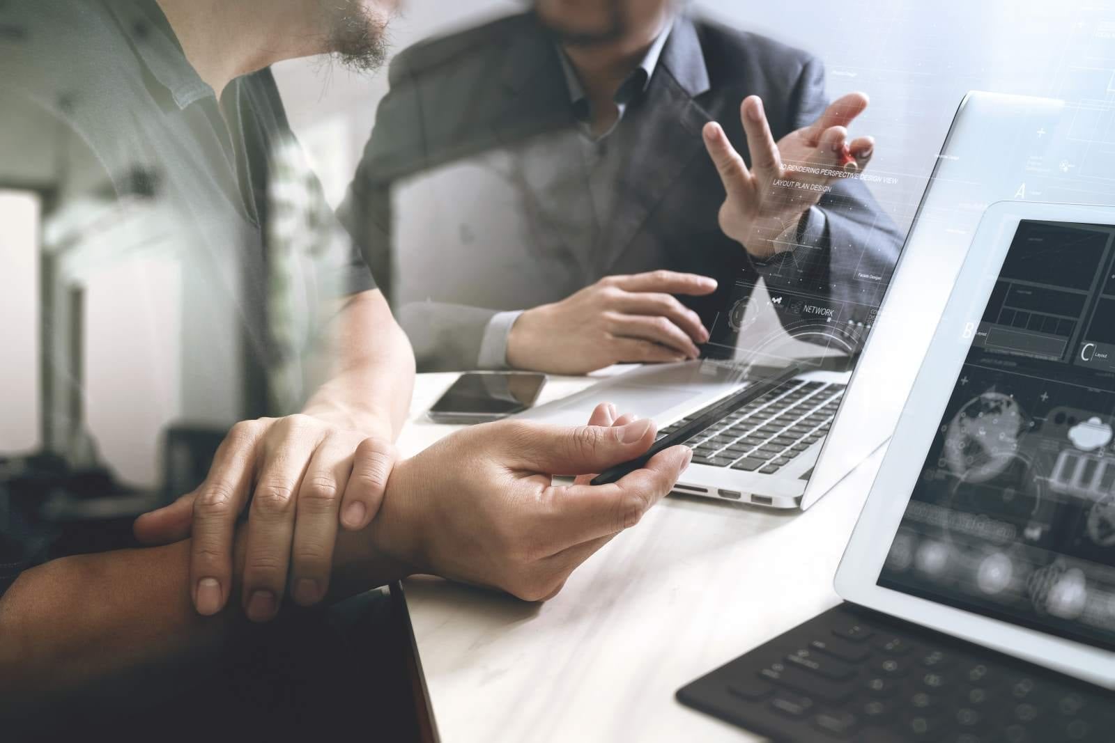 two men talking over a laptop