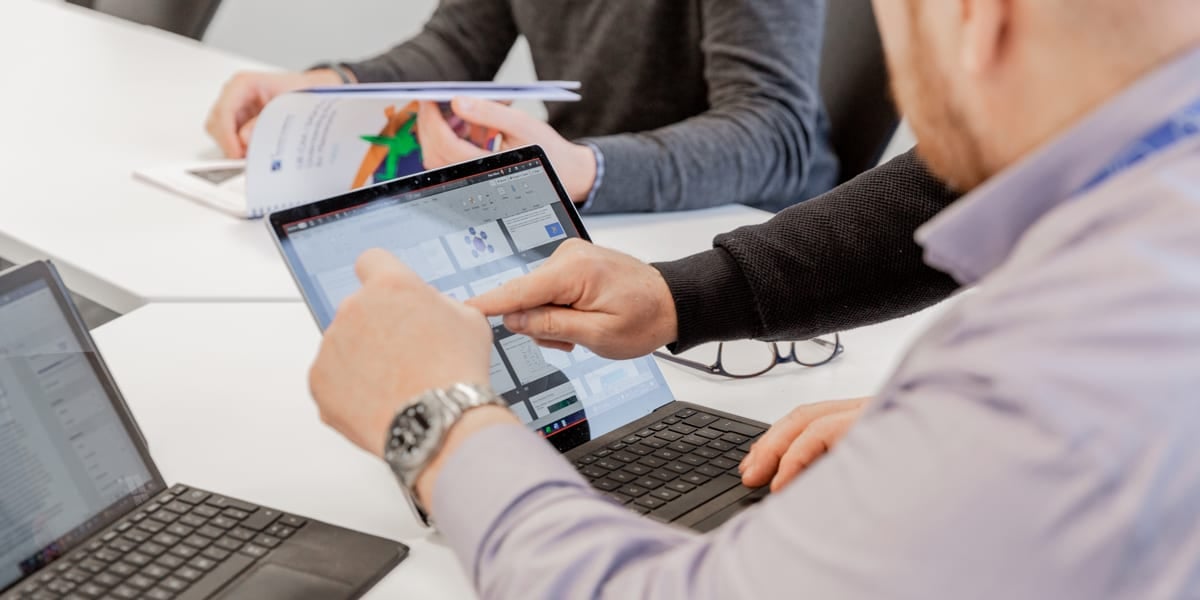 men pointing at a laptop screen